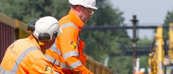 Two workers observing work on a train track