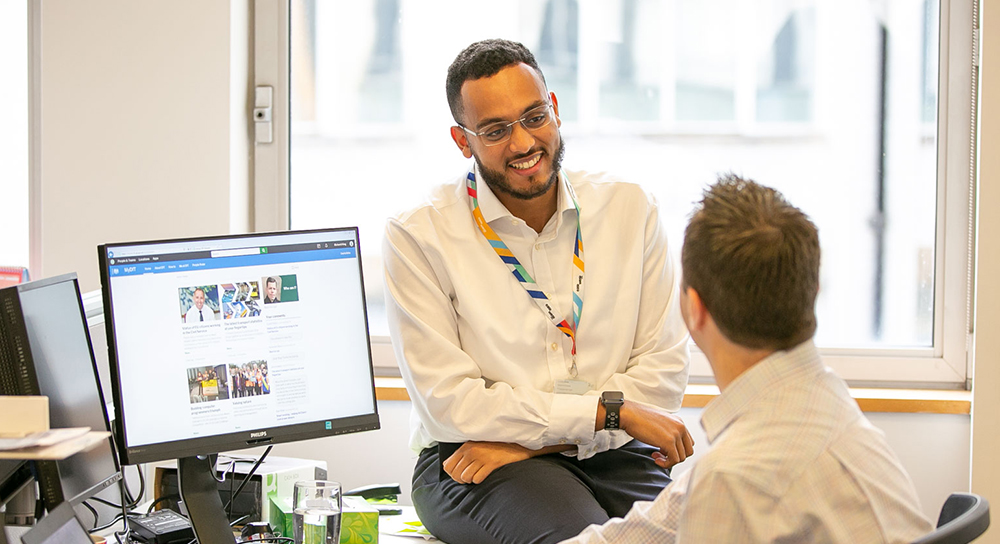 two colleagues sitting at desk on computer v2