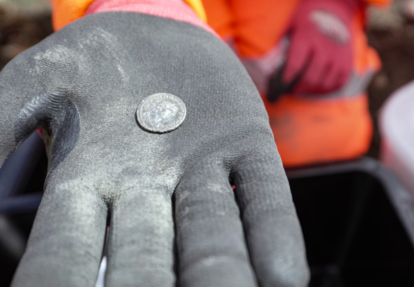 A hand up close to the camera holding a roman coin 