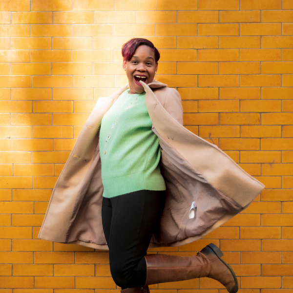 Kerene standing against yellow brick wall