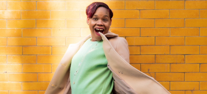 Kerene standing against yellow brick wall