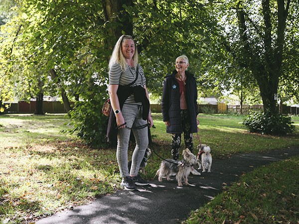 two people walking dog in park