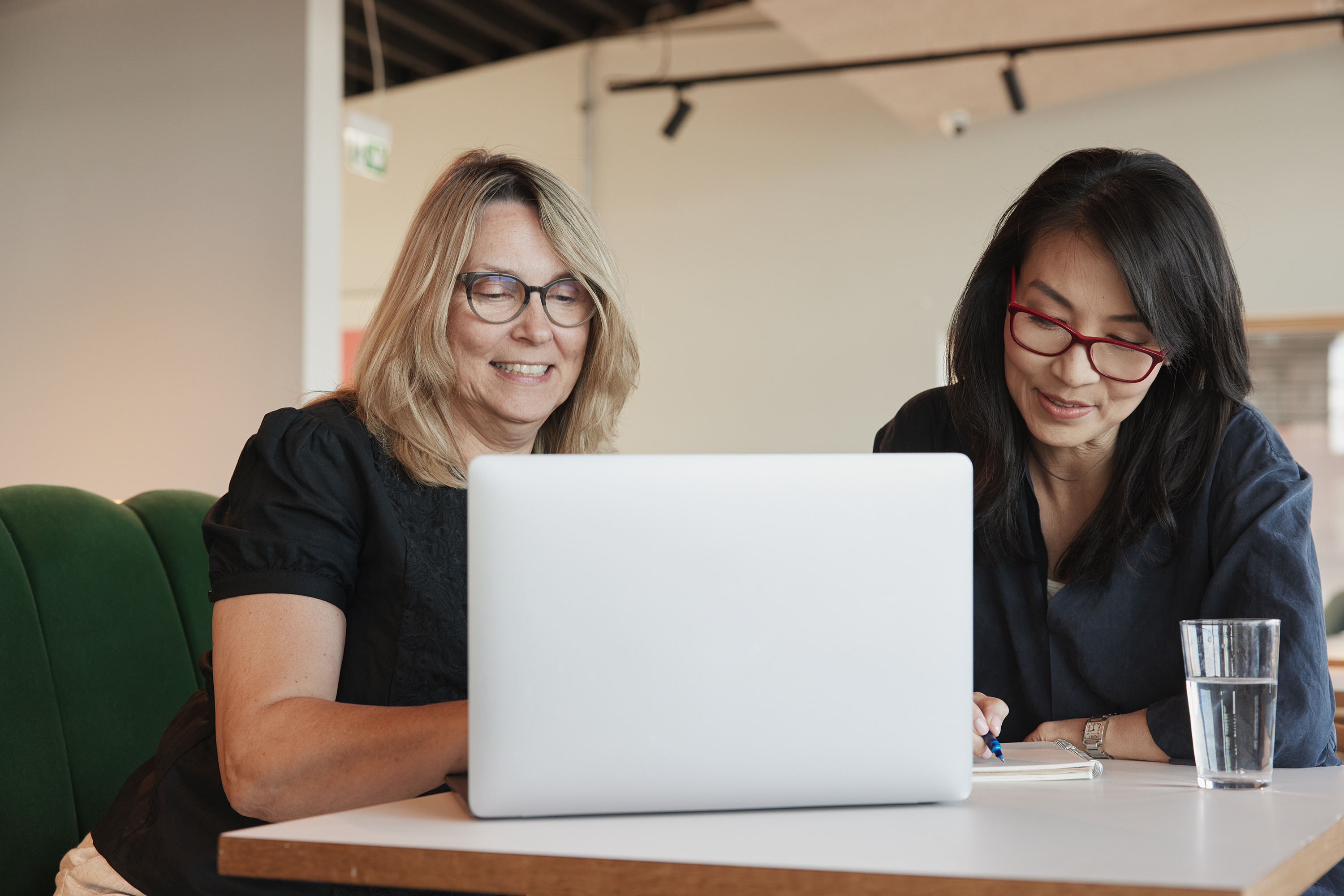 Two women sitting down working on laptop